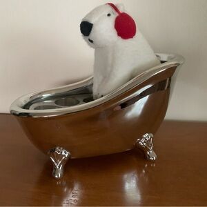 Polar bear with red earmuffs in chrome claw foot bathtub